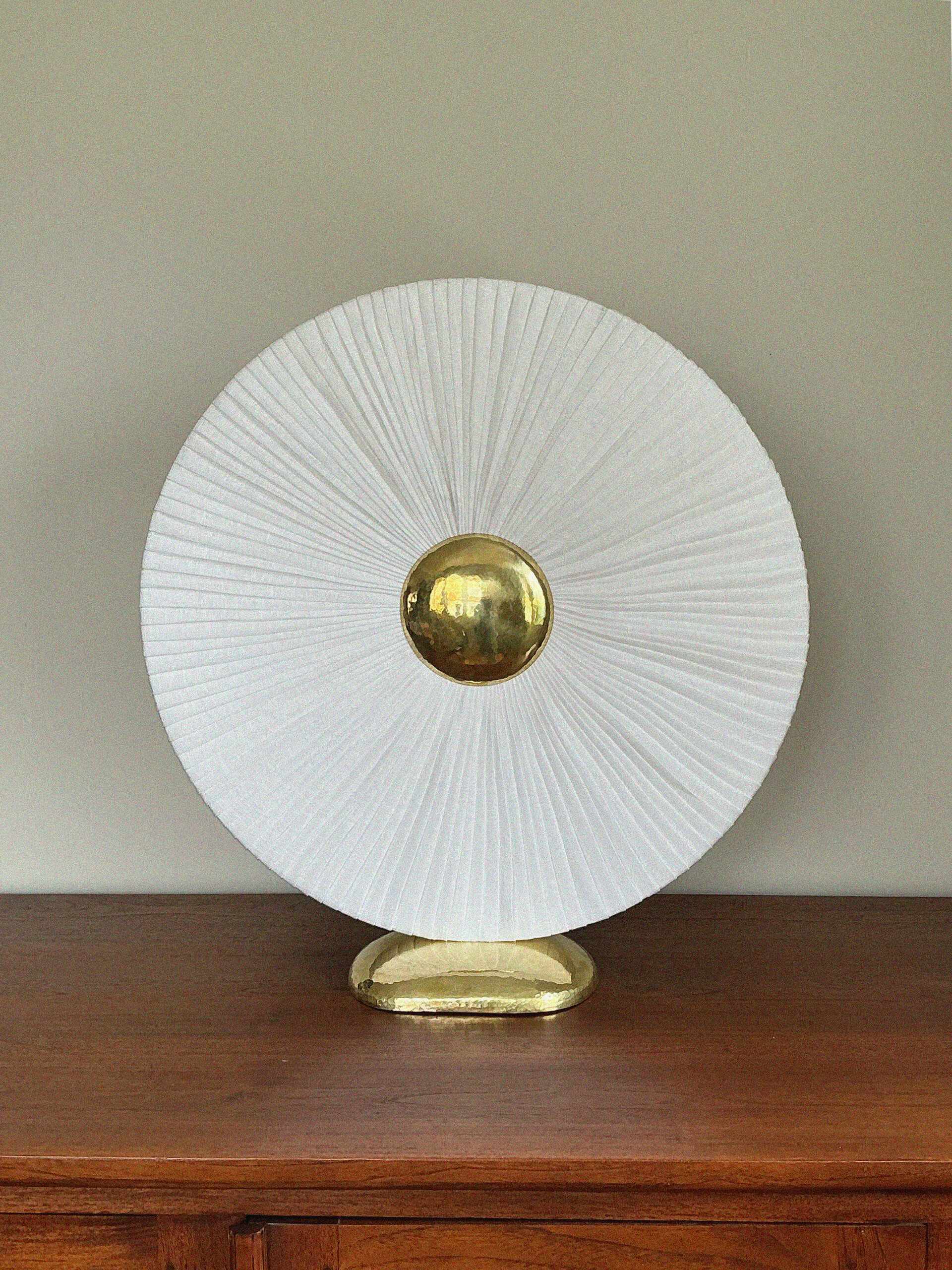 Iris éteinte : disque de lin plissé blanc et cœur de laiton martelé à la lumière du jour.