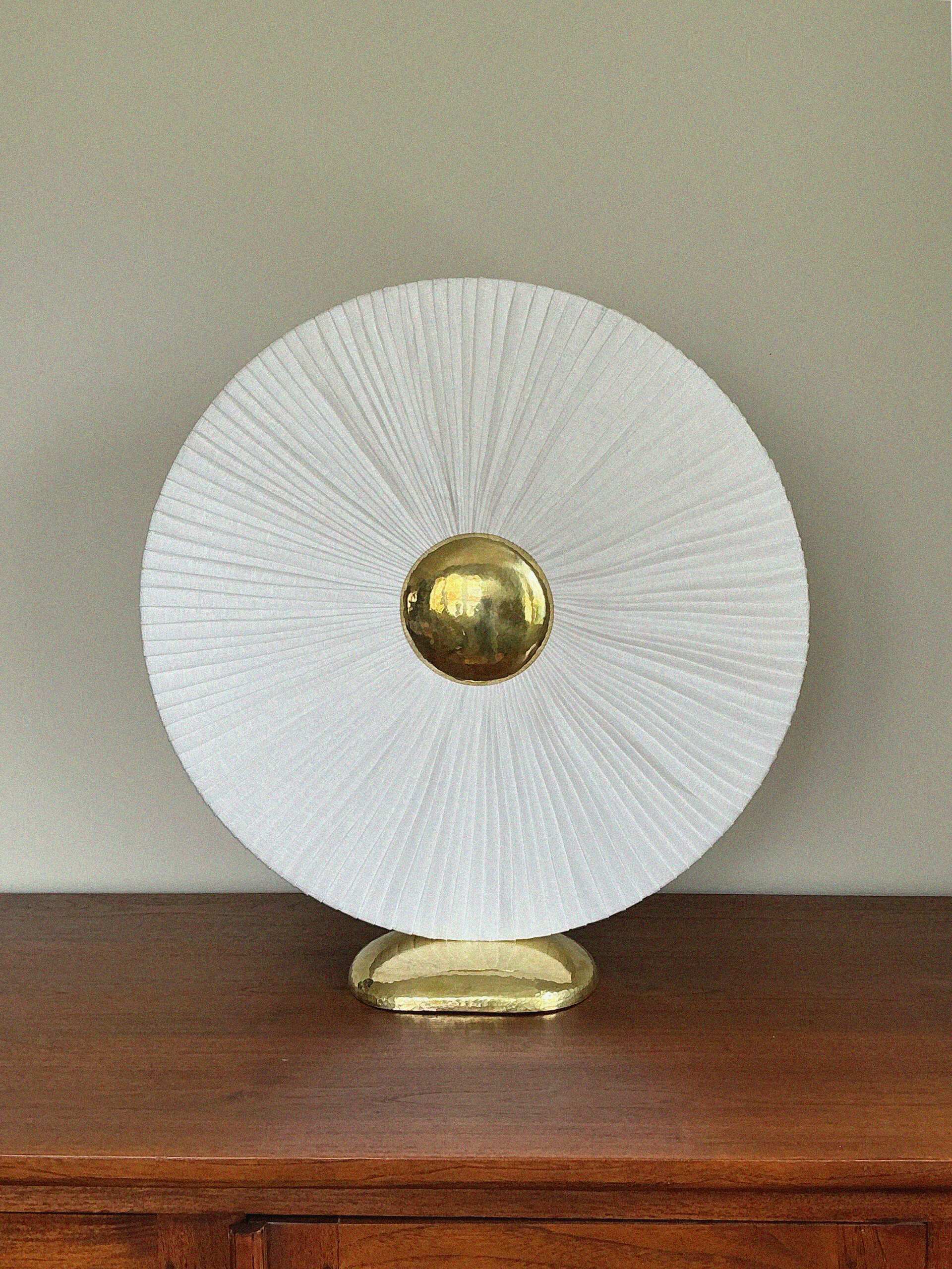 Iris éteinte : disque de lin plissé blanc et cœur de laiton martelé à la lumière du jour.
