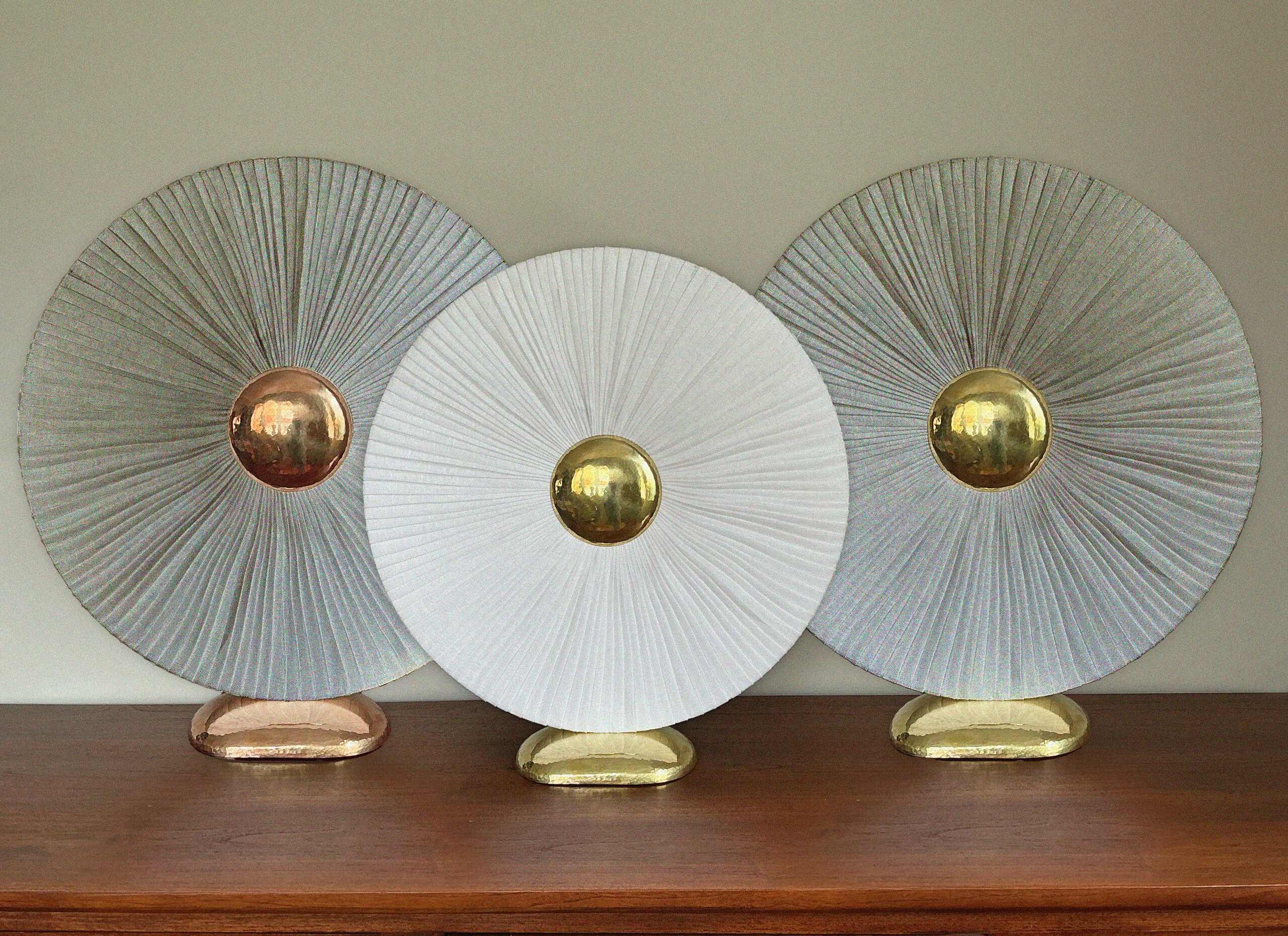 Les variantes d'Iris côte à côte : lin naturel et cuivre, lin blanc et laiton, lin naturel et laiton.